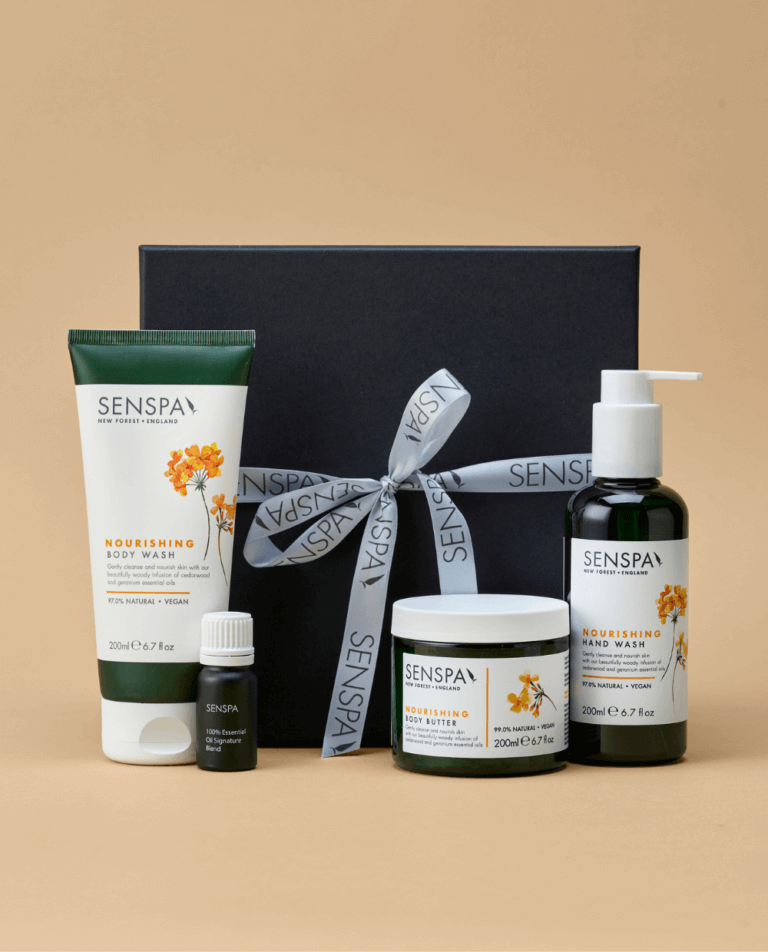 A black gift box with a SenSpa branded ribbon tied around it with a selection SenSpa Nourishing products in front of it.