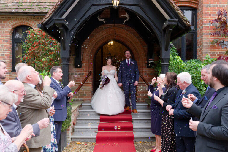 The bride and groom leave the main entrance after the ceremony to be welcomed by their guests