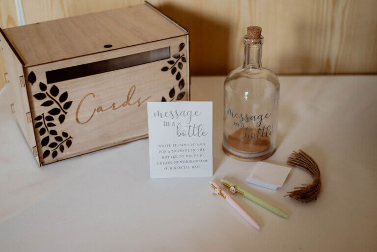 Wedding card box on table along with a pen, paper and a bottle for guests to write 'a message in a bottle to the couple'