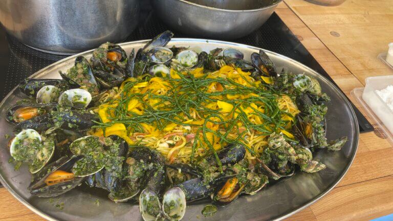 seafood linguine dish served on metal platter with samphire scattered on the top.