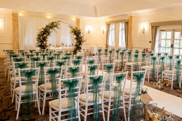 Cedar Suite set for the wedding ceremony with green chair sashes and floral moon arch