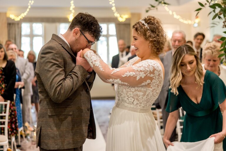 Groom kisses brides hands at the registrars table