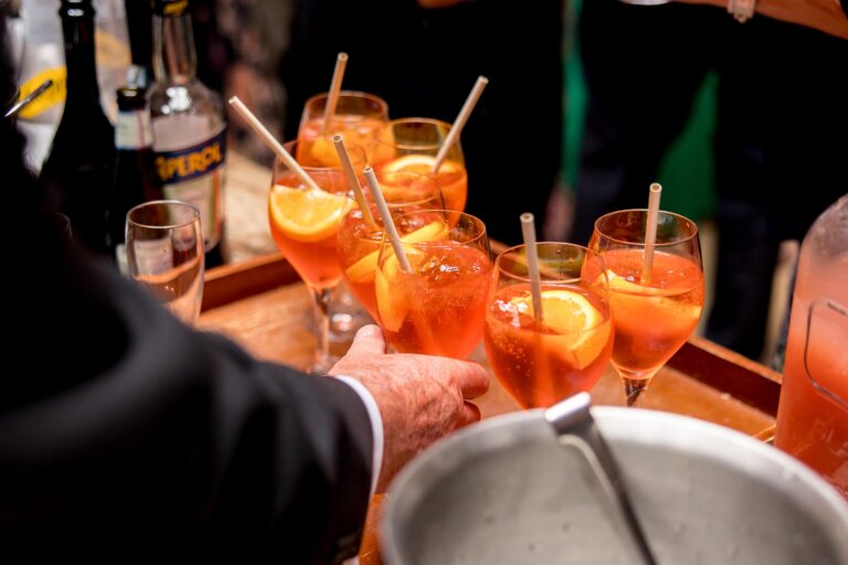 Guest takes a glass of aperol spritz from a tray