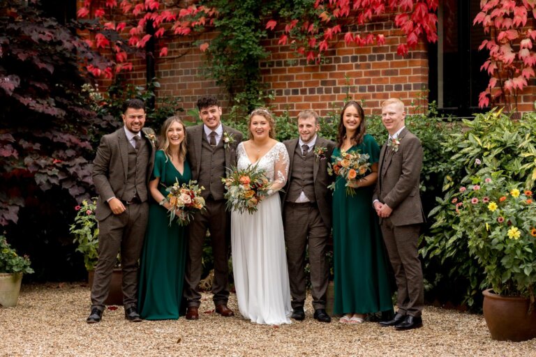 Wedding party of bridesmaids and grooms party photographed out the front of the hotel with the red ivory in the background