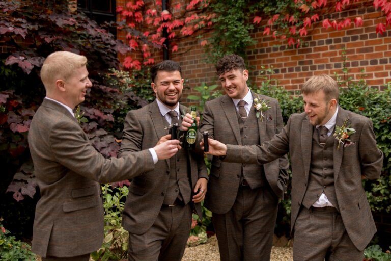 The grooms party tap their bottles together in a 'cheers' style