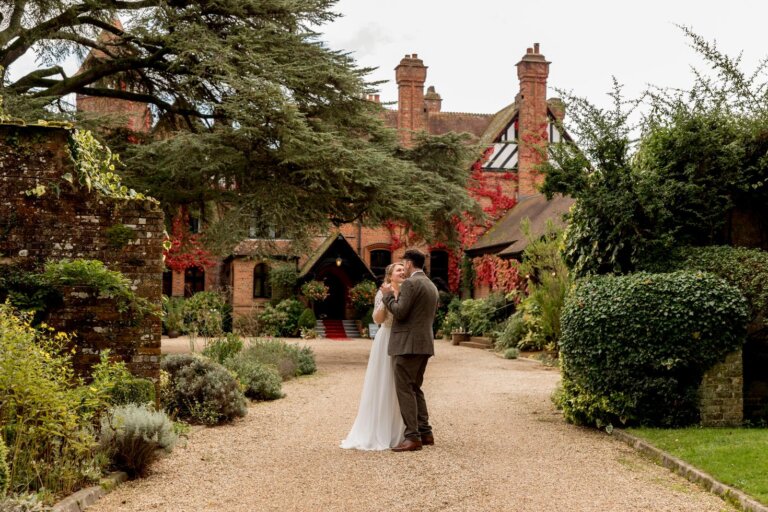 Bride and groom dance on the drive of Careys Manor with the hotel in the background