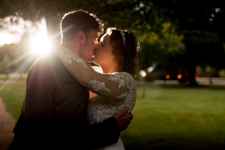 Bride and Groom Share a kiss on the front lawn as the sun sets